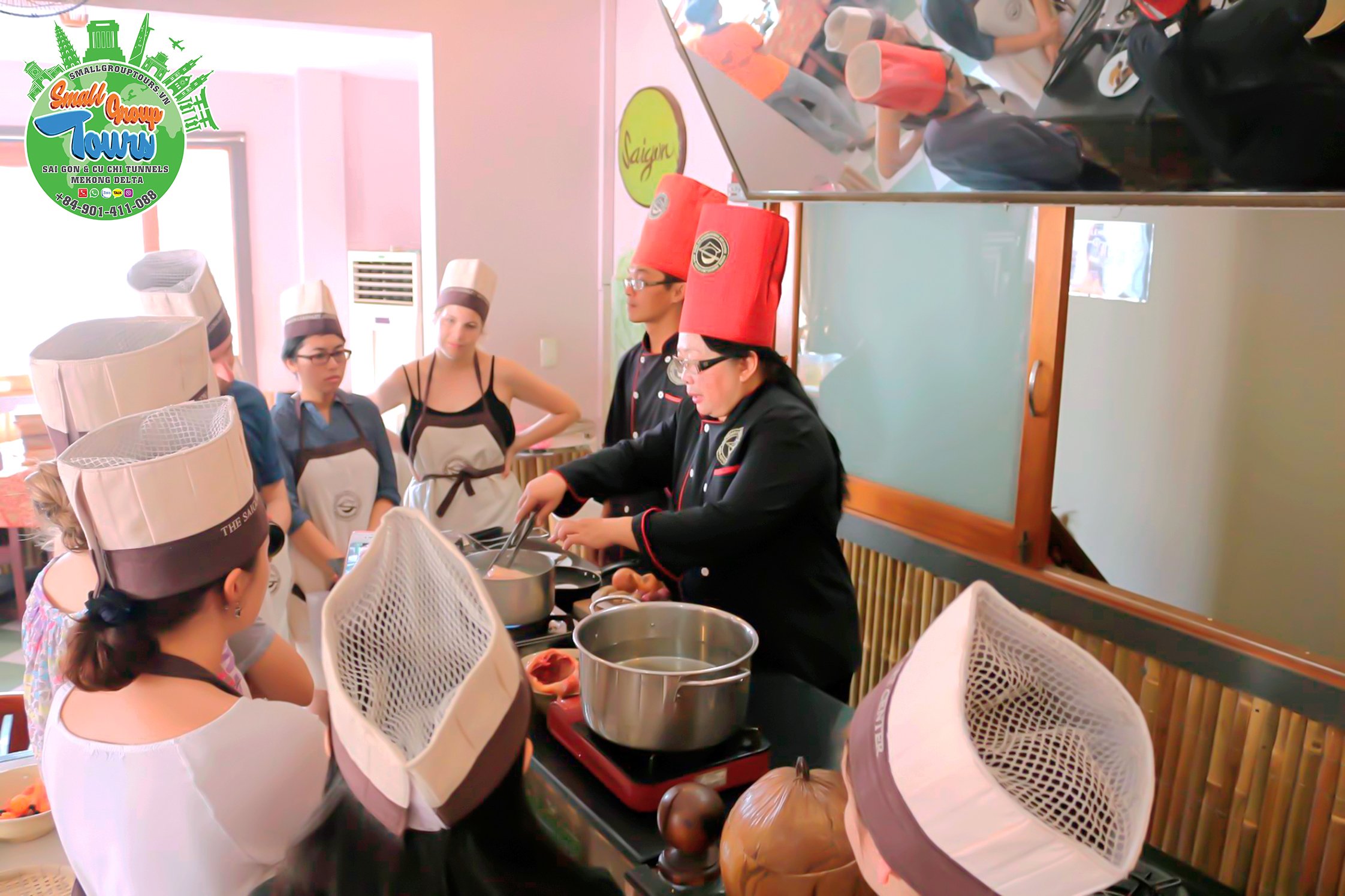 A group of eager culinary enthusiasts gathers around the chef, attentively listening to instructions during an engaging cooking class after Ben Thanh Market visit.